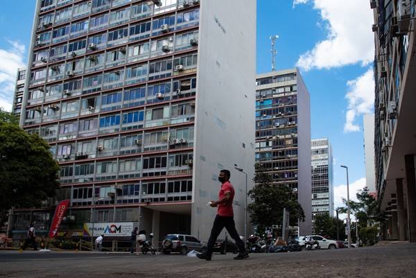 Fotografia colorida de pessoa caminhando com prédios ao fundo no Setor Comeral Sul, Brasília - Metrópoles