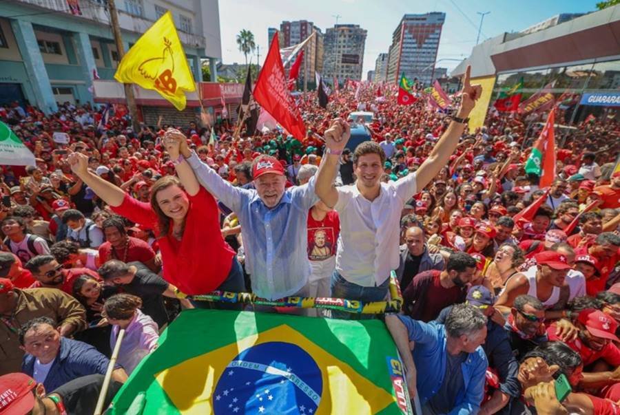Marilia Arraes, Lula e João Campos participam de carreata em Recife em apoio à candidatura do petista. Eles sorriem de cima de um carro, cercados de milhares de pessoas, e levantam os braços - Metrópoles