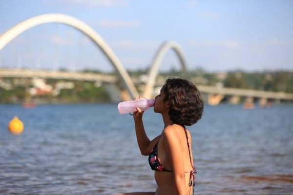 mulher bebe água proximo ao lago paranoá