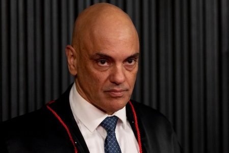 O ministro do STF e presidente do TSE, Alexandre de Moraes. Ele usa toga preta com detalhes vermelhos e olha de cima pra baixo, sério - Metrópoles