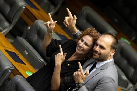 Deputada Carla Zambelli (PL-SP) posa junto ao deputado Eduardo Bolsonaro (PL-SP) no plenário da Câmara dos Deputados. Ambos fazem sinal de "arminha" com as mãos - Metrópoles