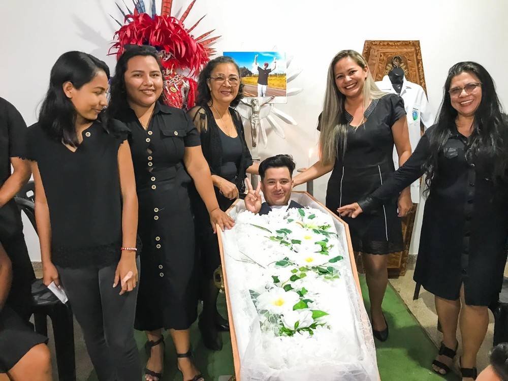 foto colorida de alunos simulando funeral com caixão e flores