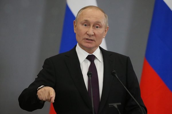 Putin impõe lei marcial nas quatro regiões anexadas na Ucrânia. Na foto, ele discursa diante de microfones, usando terno, com duas bandeiras da Rússia atrás - Metrópoles