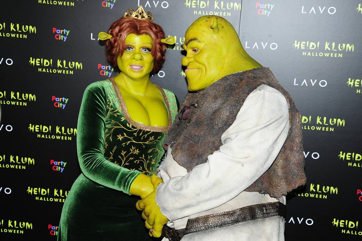 Heidi Klum e o marido, Tom Kaulitz, fantasiados como o casal Fiona e Shrek em uma festa de Halloween em 2018. Usam maquiagens verde e as roups iguais às do personagem - Metrópoles