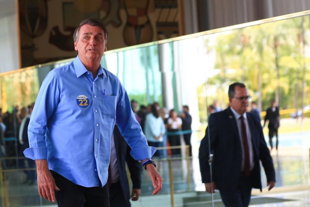 O presidente e candidato à reeleição Jair Bolsonaro caminha no Planalto em ato com apoio de políticos goianos. Ele usa camisa azul com adesivo de campanha - Metrópoles