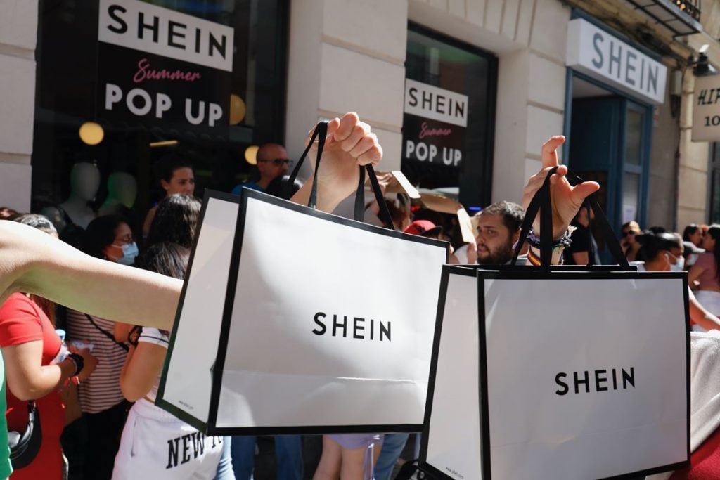 Pessoas carregam sacolas brancas com logotipo da Shein - Metrópoles