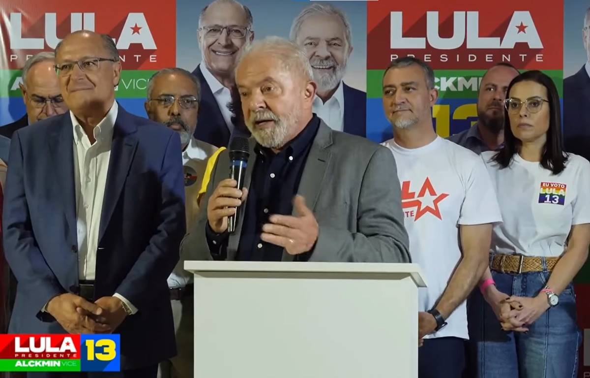 Lula faz campanha no Rio Grande do Sul e discursa ao lado de aliados e o candidato a vice-presidente, Geraldo Alckmin. Ele segura microfone diante de pulpito branco - Metrópoles