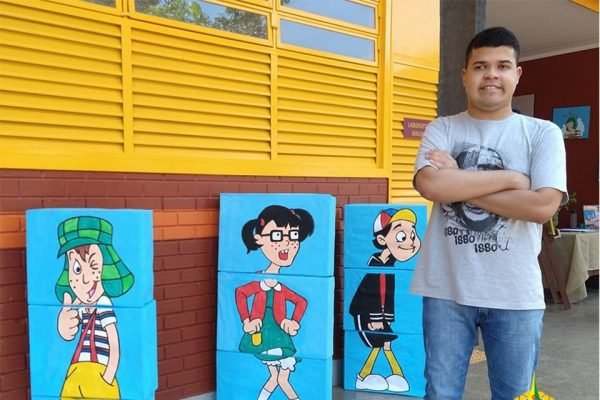 Menino ao lado de quadros em escola