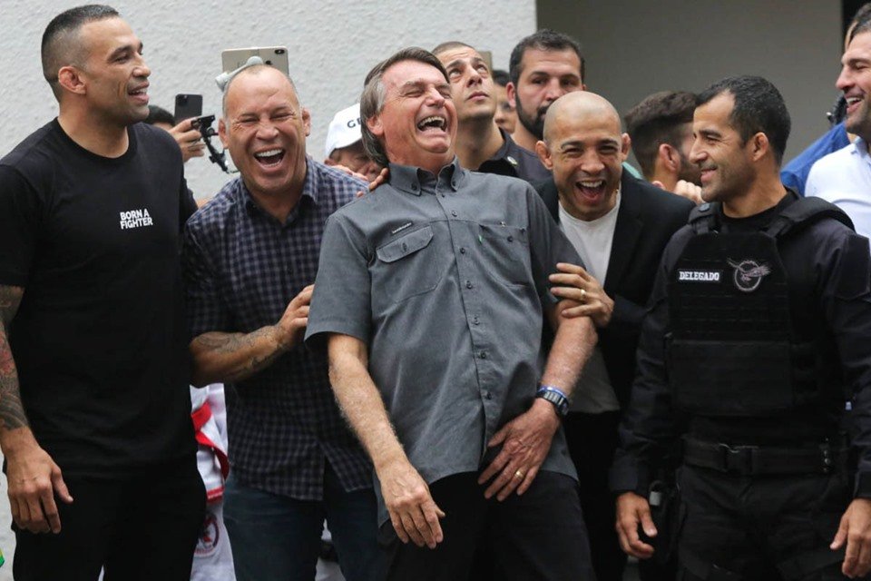 Bolsonaro ao lado de lutadores que declararam apoio à sua campanha em São Paulo. Ele ri ao lado dos pugilistas, acompanhado por uma comitiva - Metrópoles