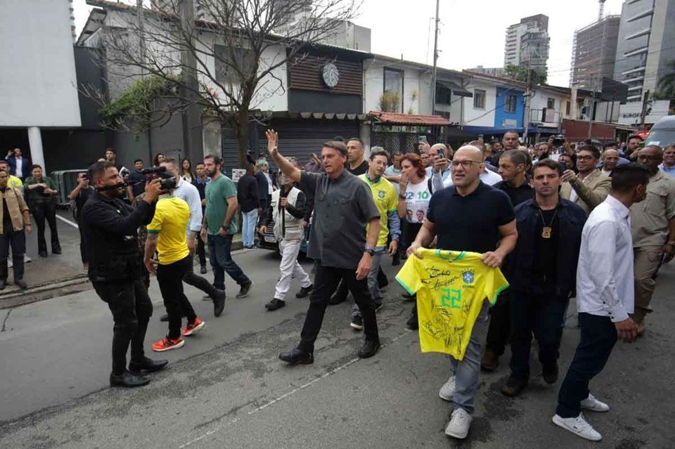 Bolsonaro ao lado de lutadores que declararam apoio à sua campanha em São Paulo. Ele caminha, acenando, ao lado dos pugilistas e acompanhado por uma comitiva - Metrópoles