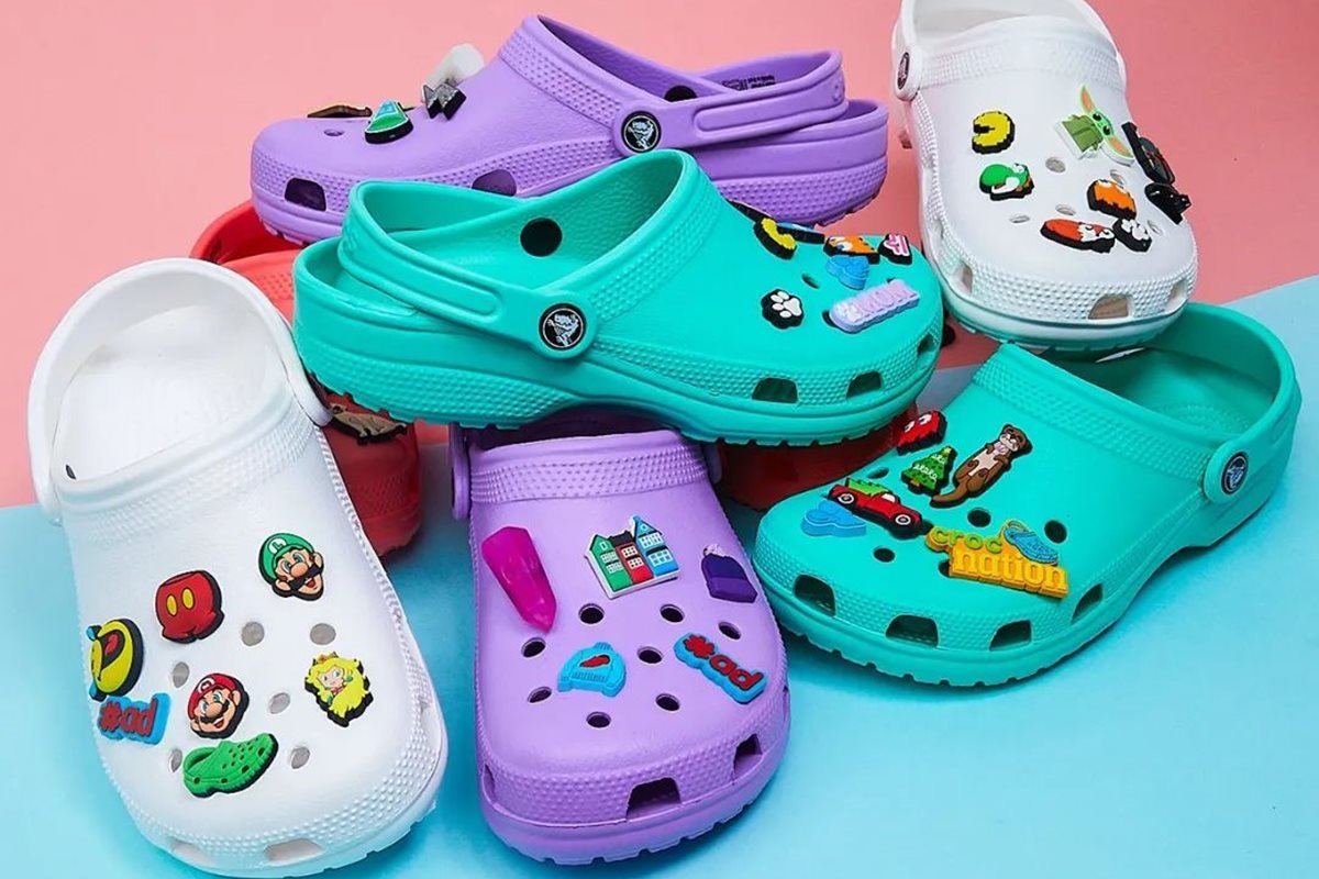 Sapatos coloridos da marca Crocs fotografados em estúdio com um fundo colorido - Metrópoles