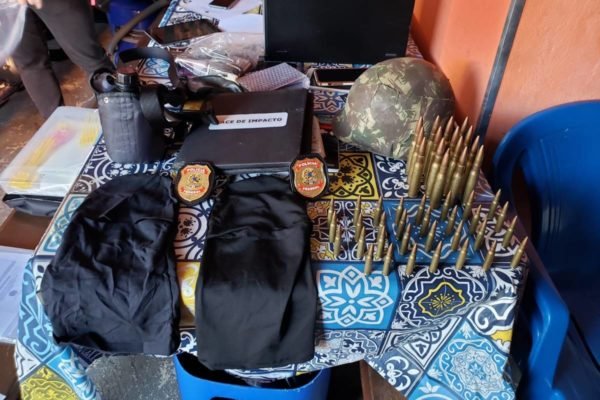 Polícia Federal investiga participantes de crime em Araçatuba. Na foto, uma série de armamentos apreendidos juntamente com vestimentas militares e celulares sob uma mesa - Metrópoles