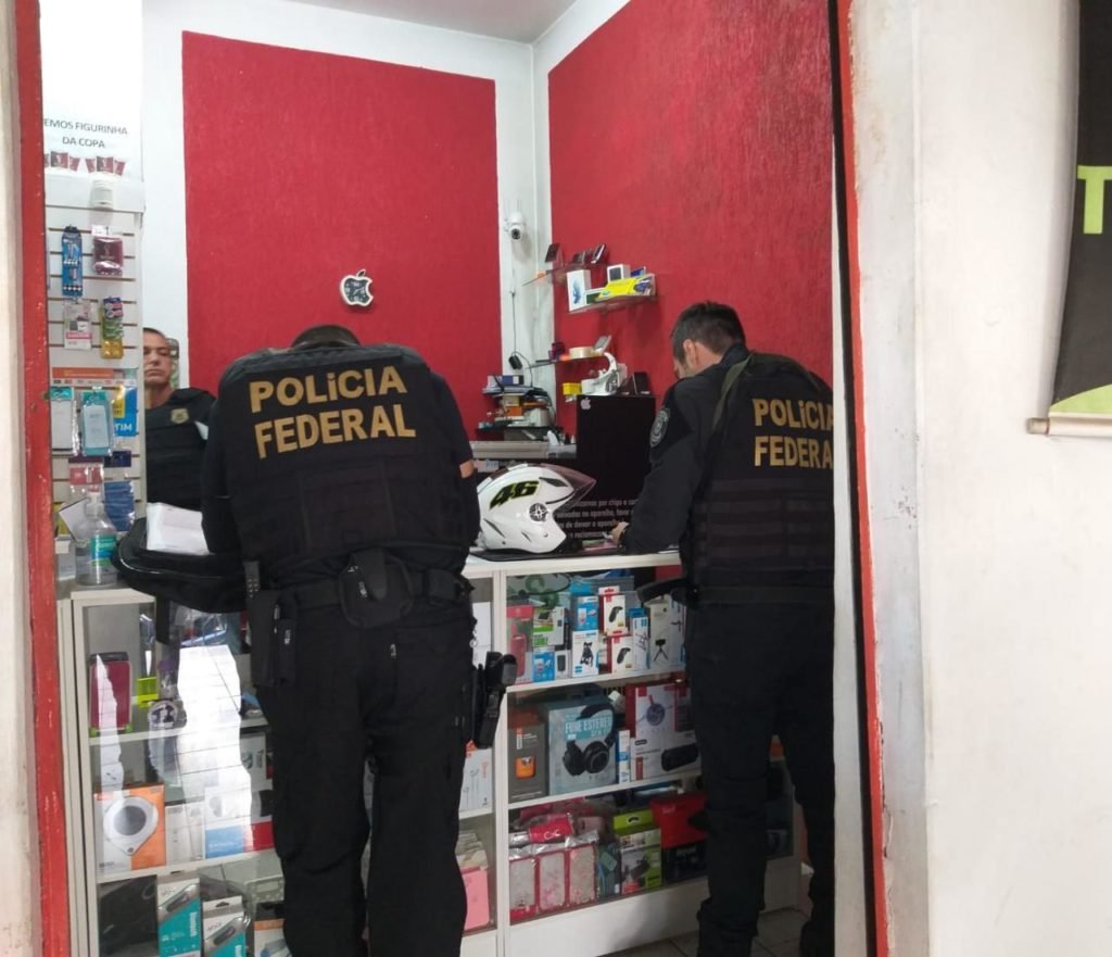 Polícia Federal investiga participantes de crime em Araçatuba. Na foto, três agentes fazem vistoria em loja de eletrônicos - Metrópoles