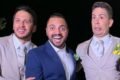 Três homens de terno sorriem para a câmera