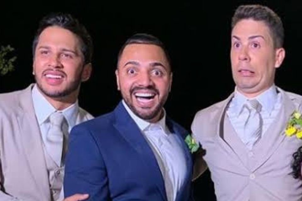 Três homens de terno sorriem para a câmera