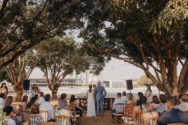 Noivos em frente a altar com convidados em espaço aberto