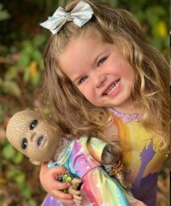 Foto colorida de Briar, uma menina de 3 anos, com sua boneca assustadora