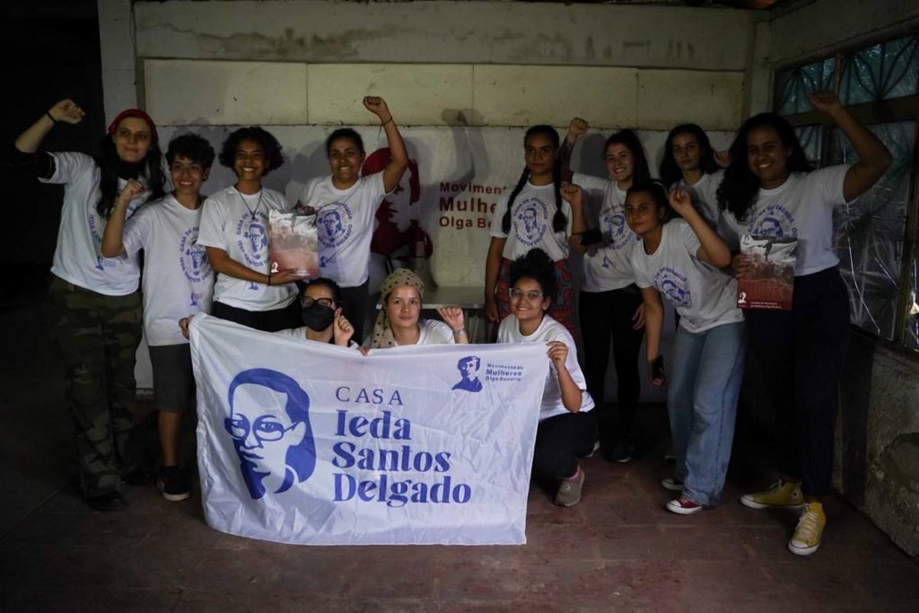 Vestidas de branco, mulheres seguram cartaz