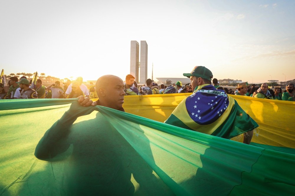 Manifestação pró-Bolsonaro na Esplanada dos Ministérios, em Brasília. Uma multidão de pessoas de diferentes idades usam roupas verde e amarela e seguram a bandeira do Brasil