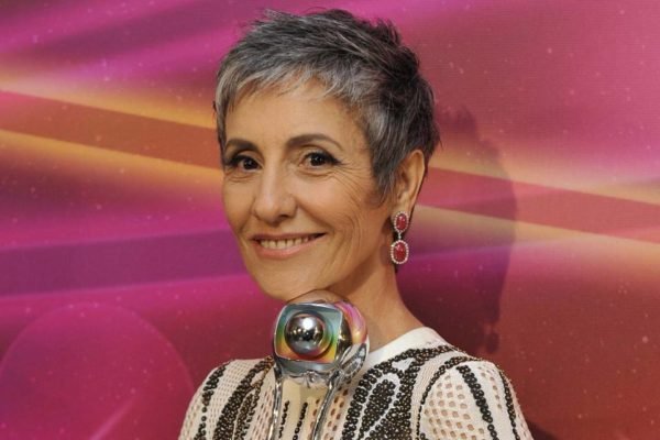 Cássia Kiss sorri segurando o prêmio Globo e sorrindo - Metrópoles