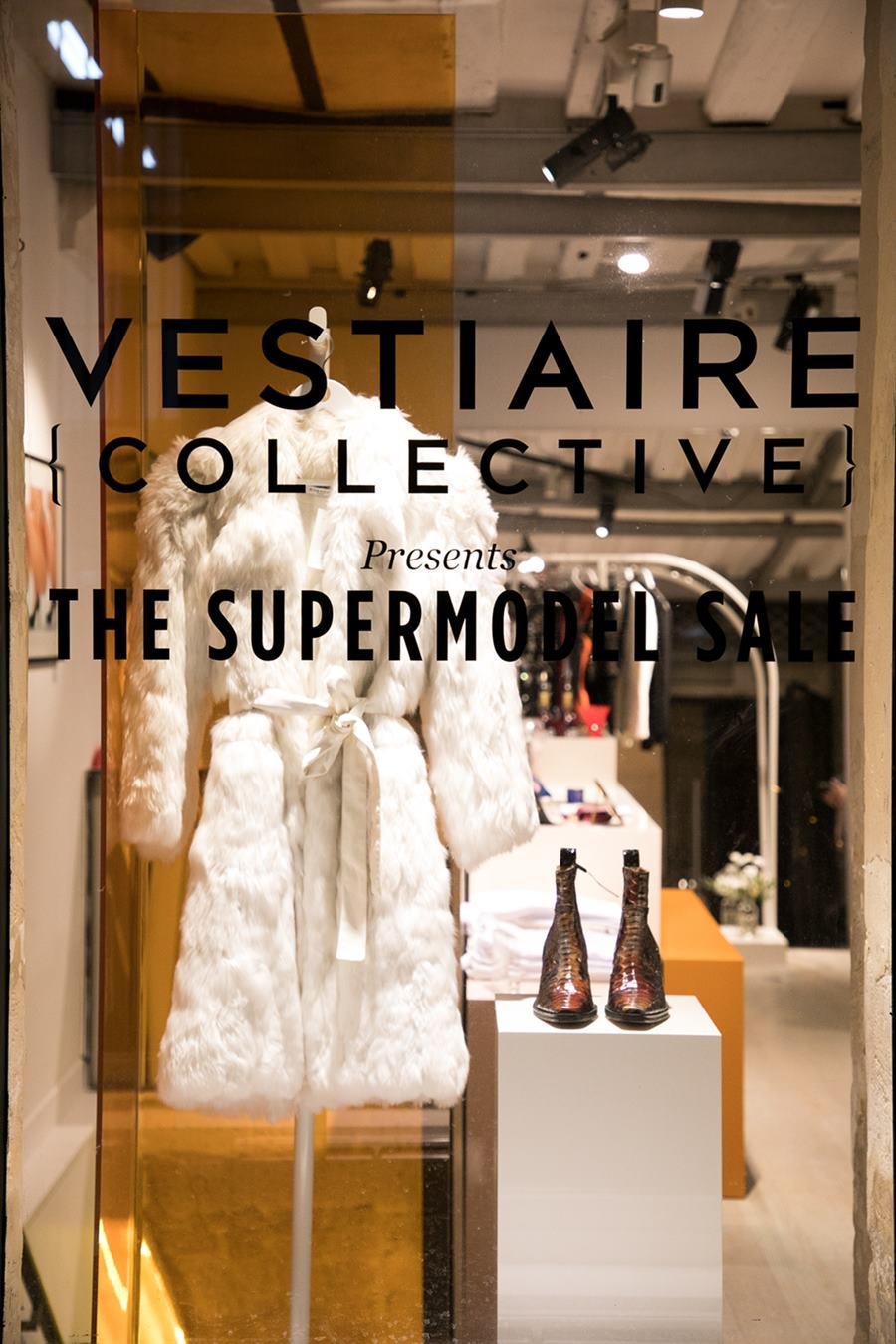 Vitrine da loja Vestiaire Collective, um brechó de luxo, em Paris, na França. Na foto é possível ver um manequimcom um casaco branco de pele para o inverno e, ao lado, uma prateleira com uma bota marrom de couro. - Metrópoles