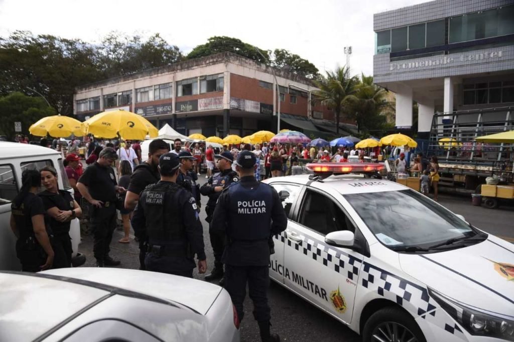 policiais militares e viaturas parados de costas