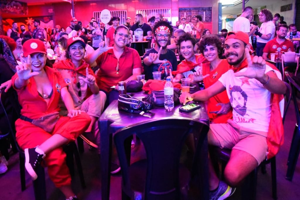 Foto de várias pessoas de vermelho sentadas em mesa de bar