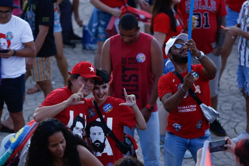 Foto de várias pessoas de vermelho fazendo símbolo do Lula
