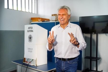 Governador Ronaldo Caiado (UB), de Goiás, sorri fazendo dois Vs com os dedos das mãos diante de uma urna eletrônica durante votação nas eleições 2022, no segundo turno
