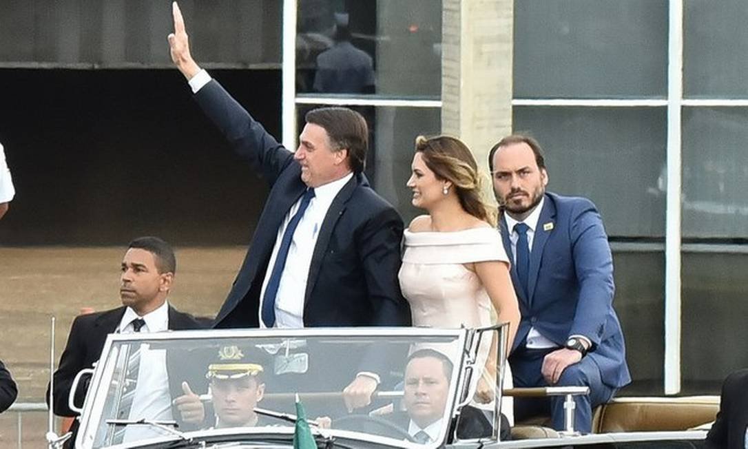 Jair, Michelle e Carlos Bolsonaro na posse do presidente em 2019, dentro de um carro Rolls Royce, acenando para o público - Metrópoles