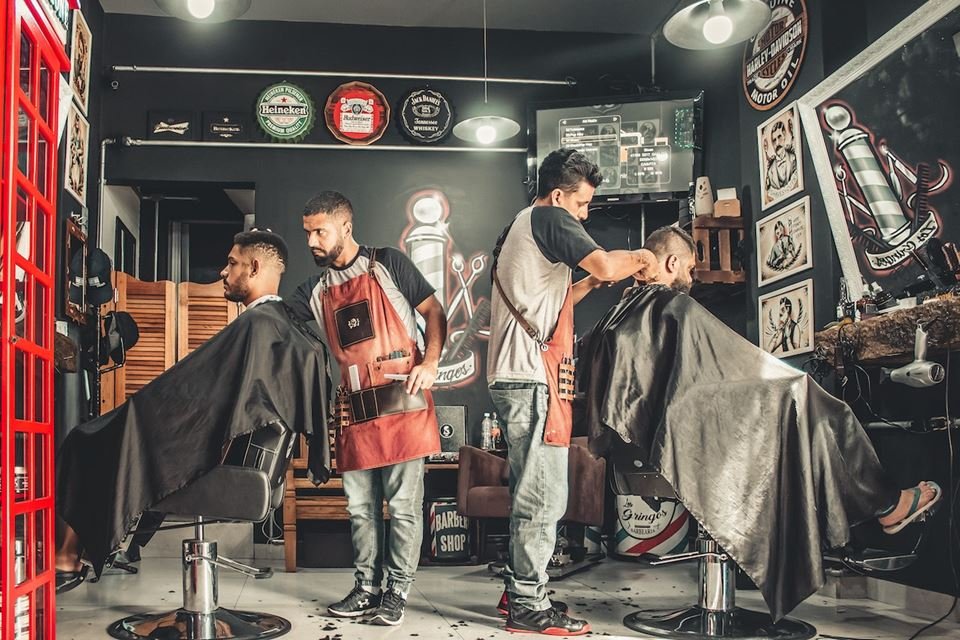 Barbeiros fazendo cortes em clientes em barbearia
