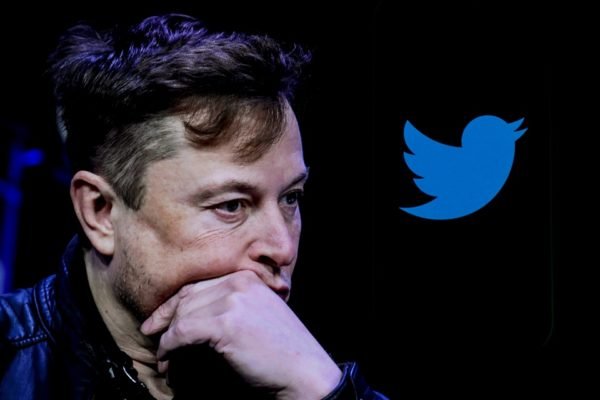 Elon Musk, dono do Twitter, aparece pensativo ao lado de um logo da rede social. Ele poderá cobrar pelo selo de verificado - Metrópoles