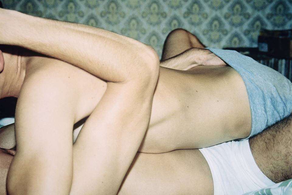 Casal de homens um em cima do outro se beijando na cama - Metrópoles