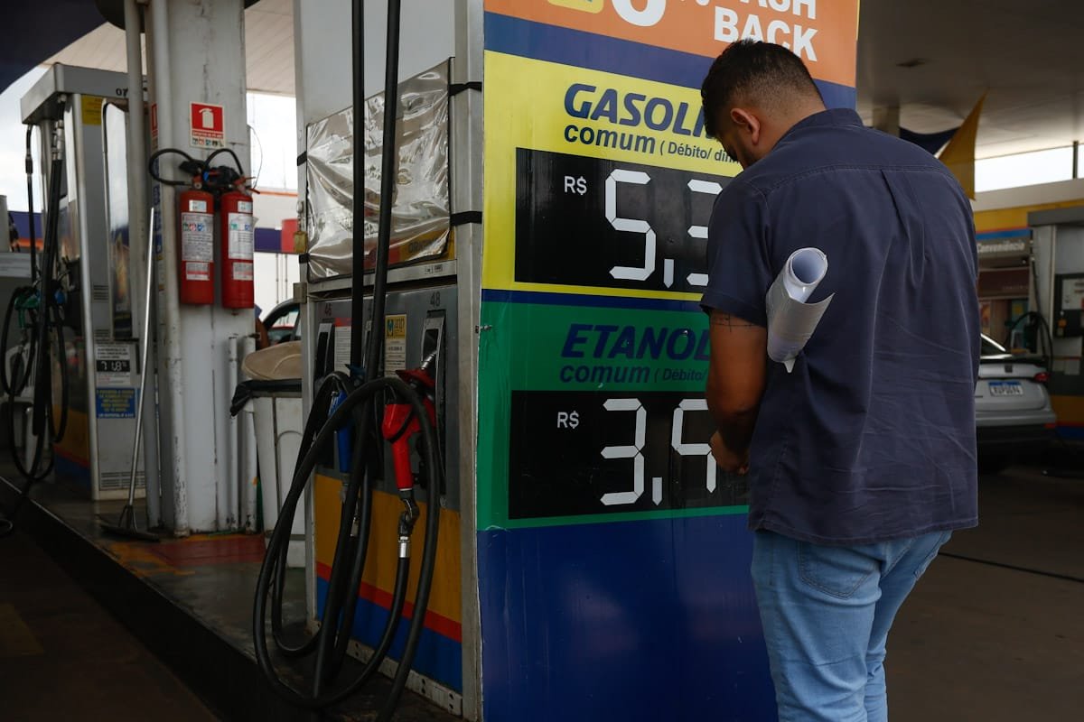 Frentista de posto de gasolina muda preço de combustíveis em placa afixada perto da bomba no Distrito Federal - Metrópoles
