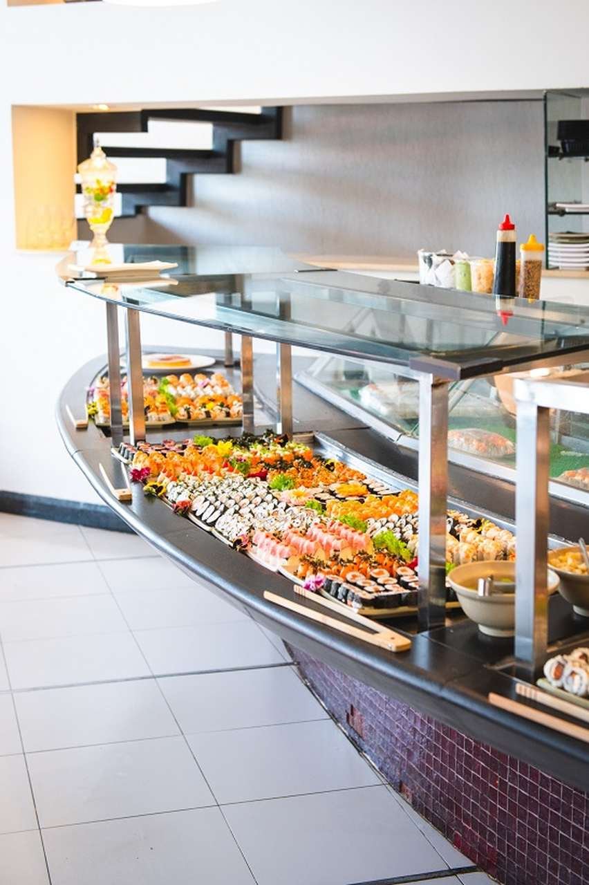Mesa de buffet de restaurante com uma grande variedade de sushi exposta - Metrópoles
