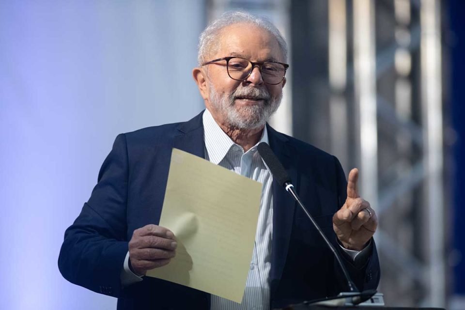 Luiz Inácio Lula da Silva discursa usando oculos e segurando um documento nas maos
