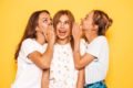 amigas fofocando, fundo amarelo, garotas de blusa branca - metrópoles
