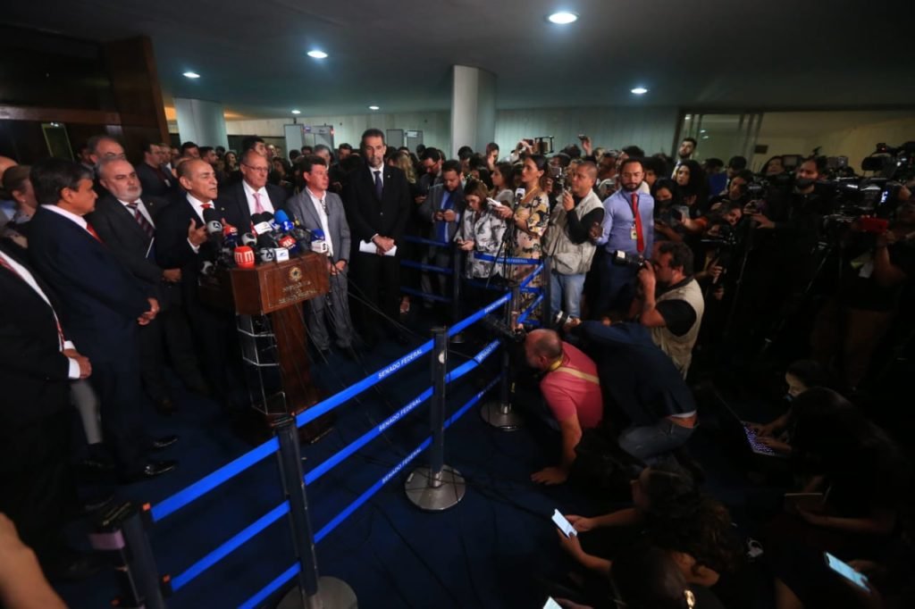 O coordenador da equipe de transição de Lula e vice-presidente eleito, Geraldo Alckmin, dá entrevista diante de púlpito no Senado cercado de outros políticos e imprensa - Metrópoles