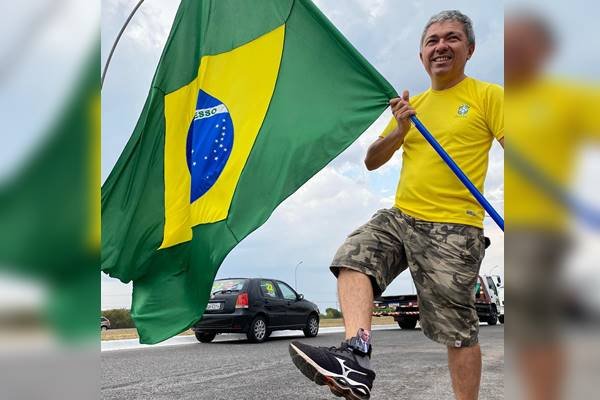 Fotografia colorida de homem que segura bandeira do Brasil. Ele é militante bolsonarista Wellington Macedo suspeito de bomba - Metrópoles
