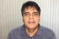 Fotografia colorida de homem de camisa polo e cabelo preto bagunçado