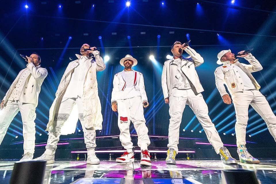 A boyband norte-americana Backstreet Boys, com roupas brancas, cantam durante show no Canadá - Metrópoles