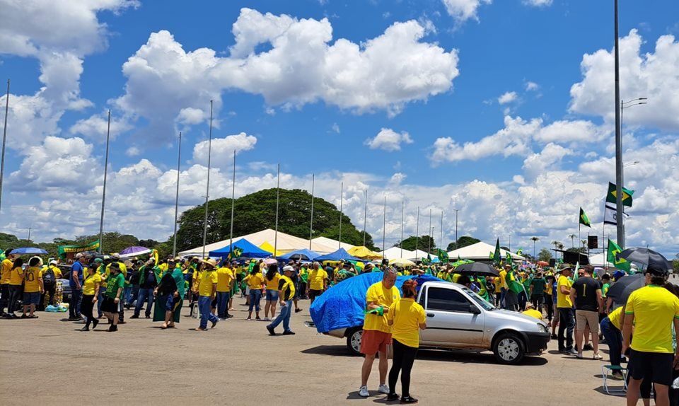 Apoiadores do presidente derrotado nas eleições Jair Bolsonaro com camisas amarelas e barracas com bandeiras do Brasil no QG do Exército, em Brasília. O céu está azul e com nuvens - Metrópoles