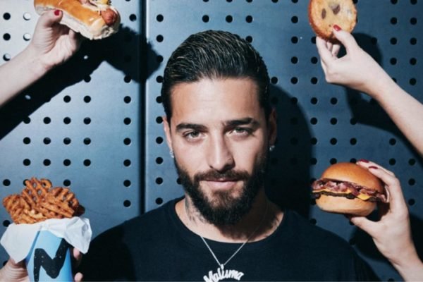 Na foto, o cantor Maluma posa para a câmera rodeado de comidas de fast-food - Metrópoles