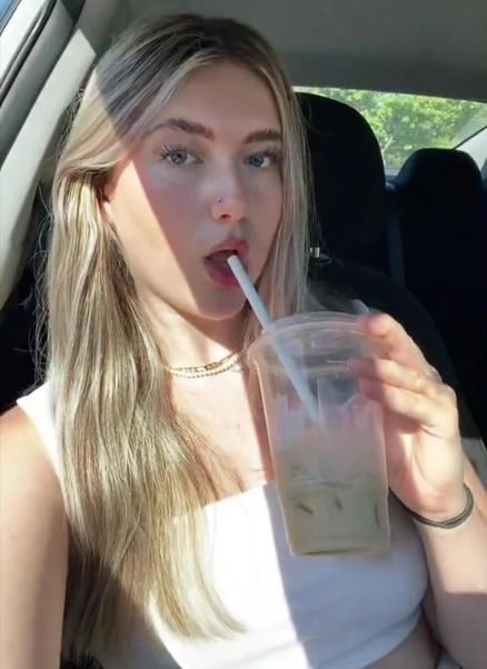 Foto colorida de menina loira tomando café gelado