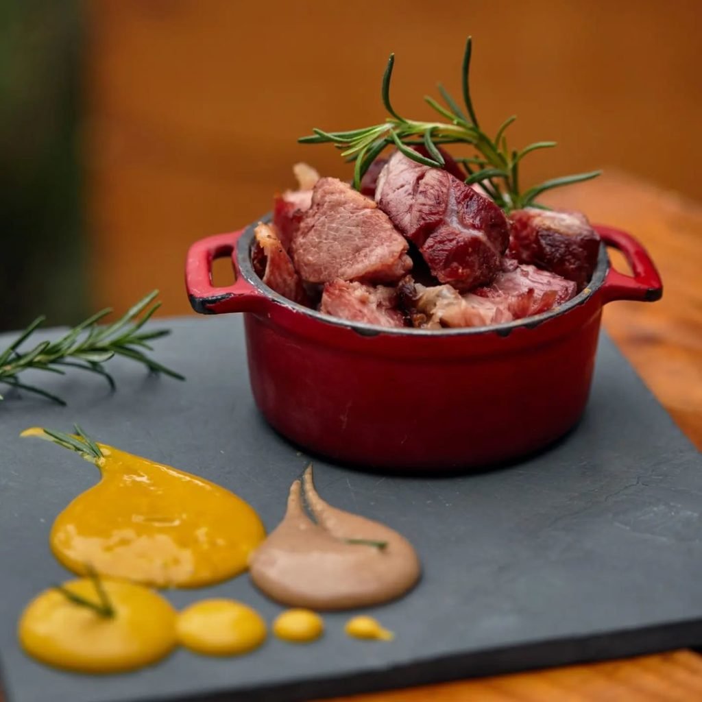 Foto de uma pequena penelinha com carne em cima de um prato com molhos coloridos
