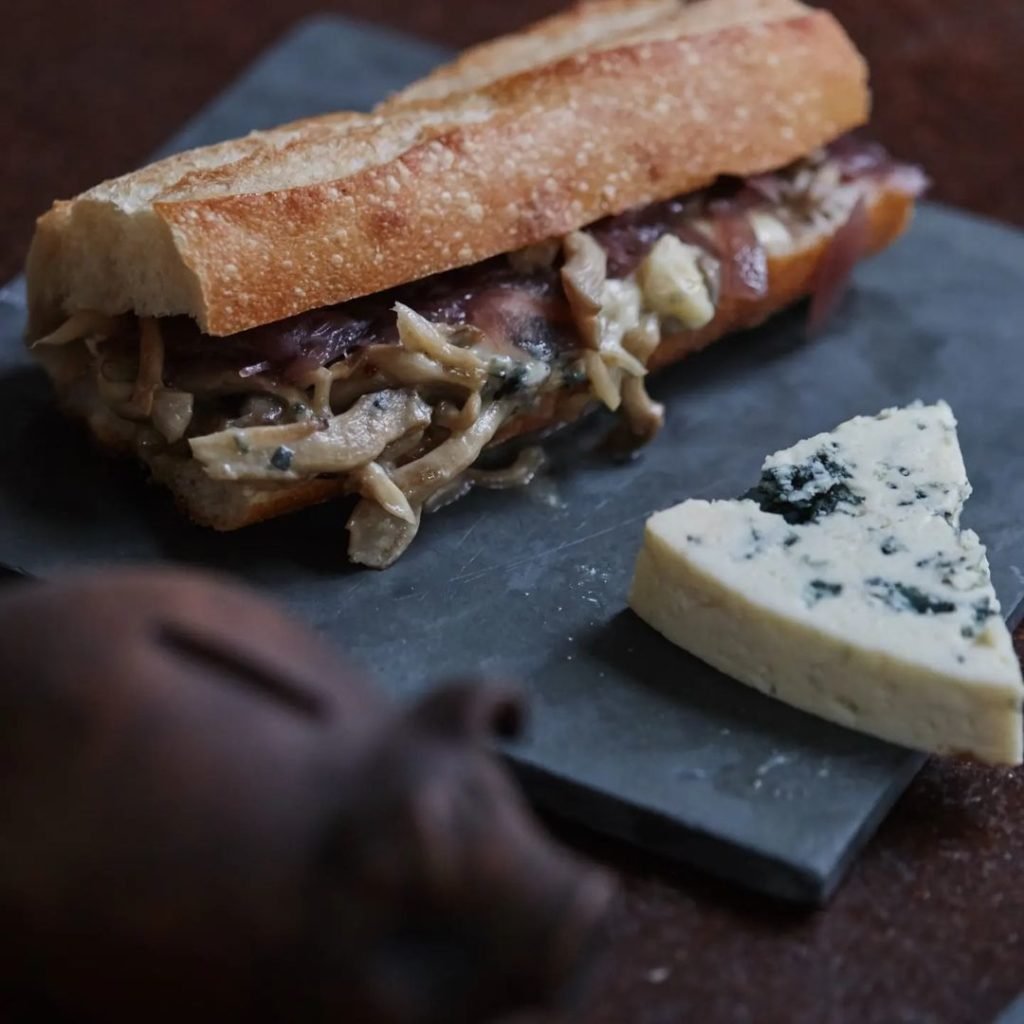 Foto de um pão recheado ao lado de uma generosa fatia de queijo gorgonzola