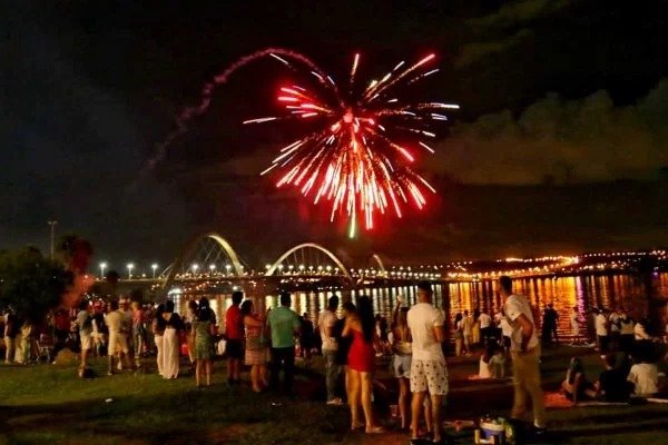 Fogos no céu de Brasília, ponte JK ao fundo e pessoas olhando em beira do lago
