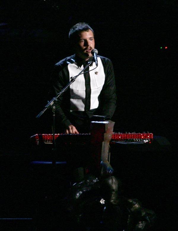 Brandon Flowers usando terno preto e branco em show - Metrópoles
