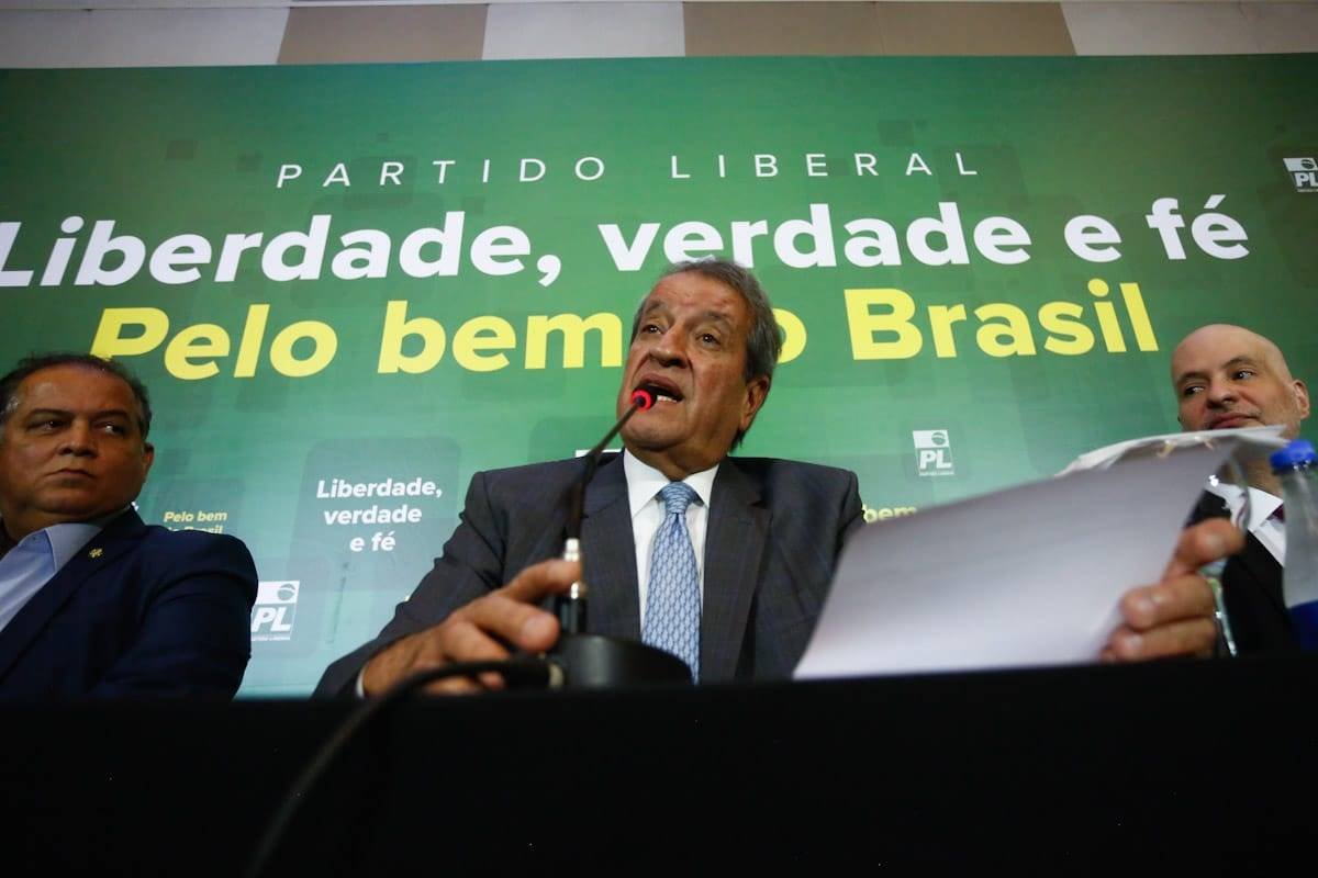 Presidente do PL, Valdemar Costa Neto declara oposição do PL ao governo do presidente eleito Lula durante coletiva de imprnesa. Ele fala em microfone, segurando papel e com painel atrás nas cores verde e amarelo - Metrópoles