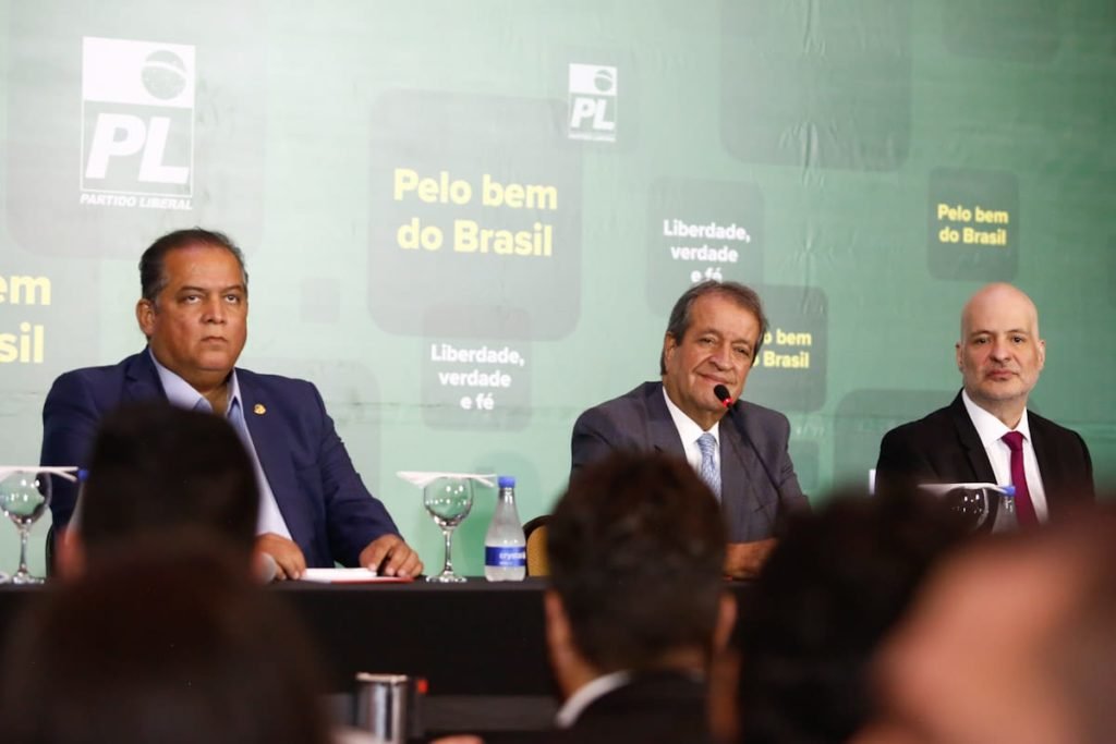 Presidente do PL, Valdemar Costa Neto declara oposição do PL ao governo do presidente eleito Lula durante coletiva de imprnesa. Ele fala em microfone, sorrindo e com painel atrás nas cores verde e amarelo - Metrópoles